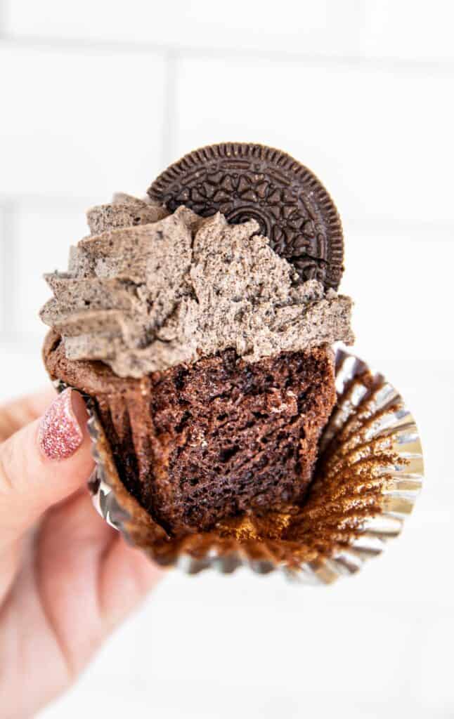 holding a chocolate cupcake with oreo buttercream frosting
