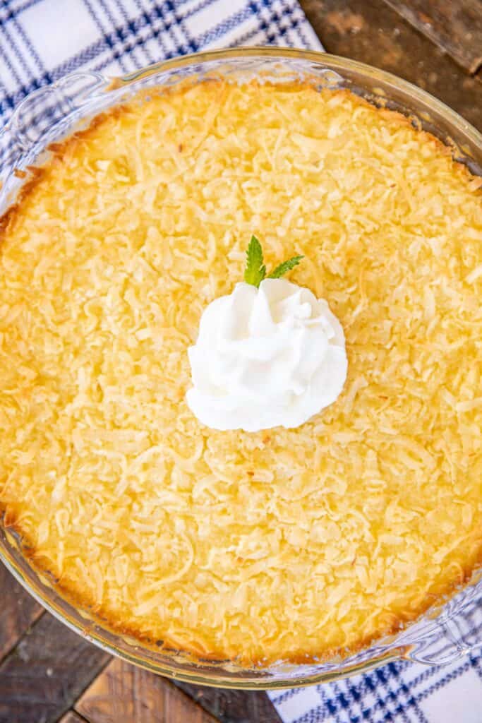 whole coconut pie topped with whipped cream on a table