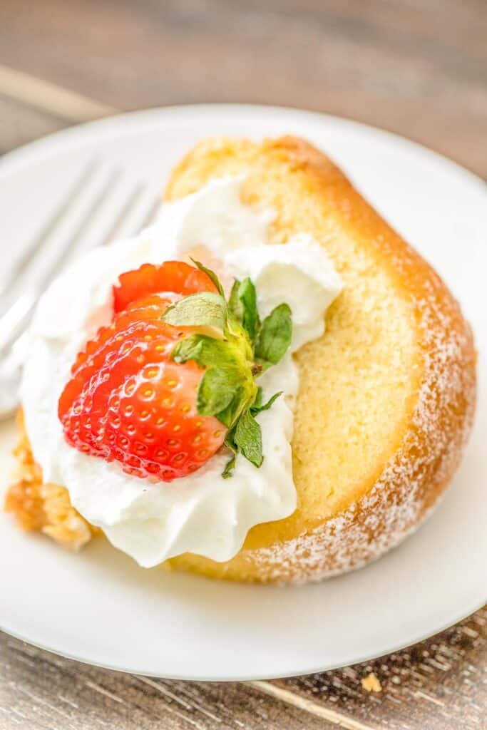 slice of pound cake on a plate topped with whipped cream and strawberries
