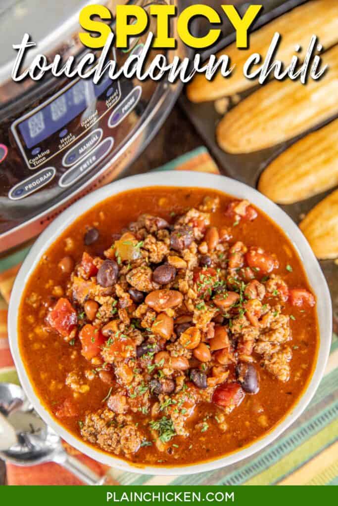 bowl of spicy chili with cornbread and a slow cooker in the back