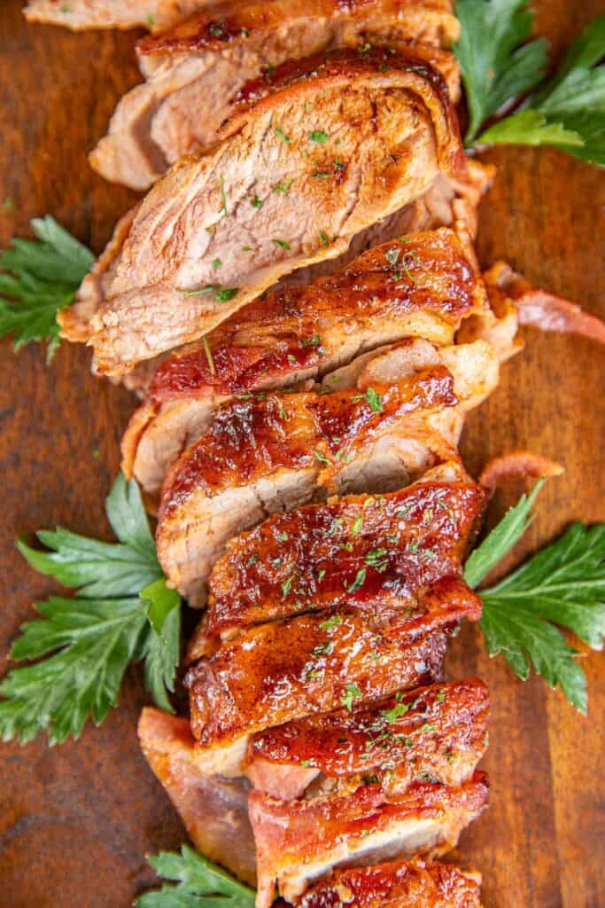 sliced bacon wrapped pork tenderloin on a platter