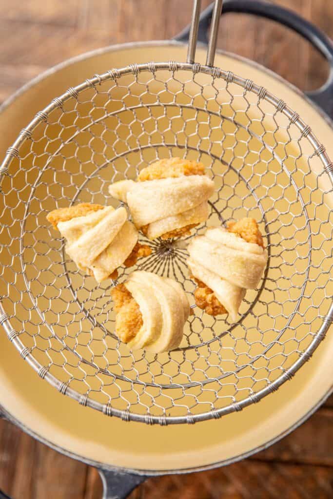 crescent roll wrapped chicken nuggets in a strainer