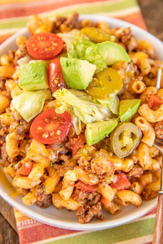 plate of macaroni and beef casserole topped with avocado and tomatoes