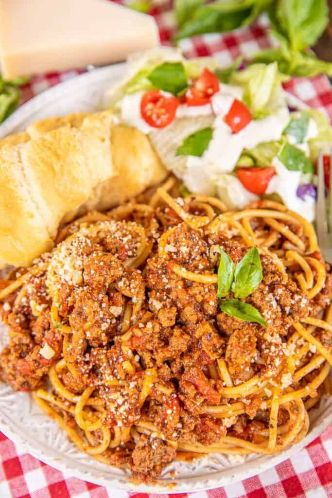 plate of spaghetti with rolls and salad
