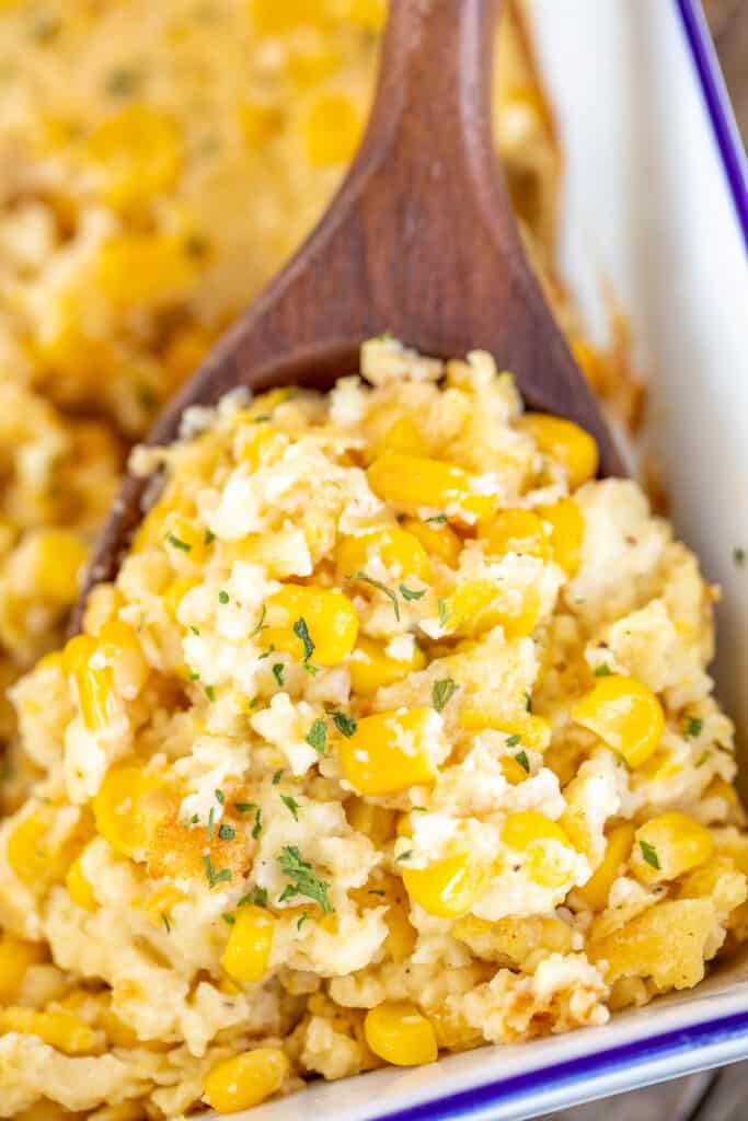scooping corn pudding casserole from baking dish