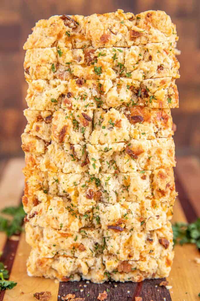 slices of bacon cheddar beer bread stacked on a board