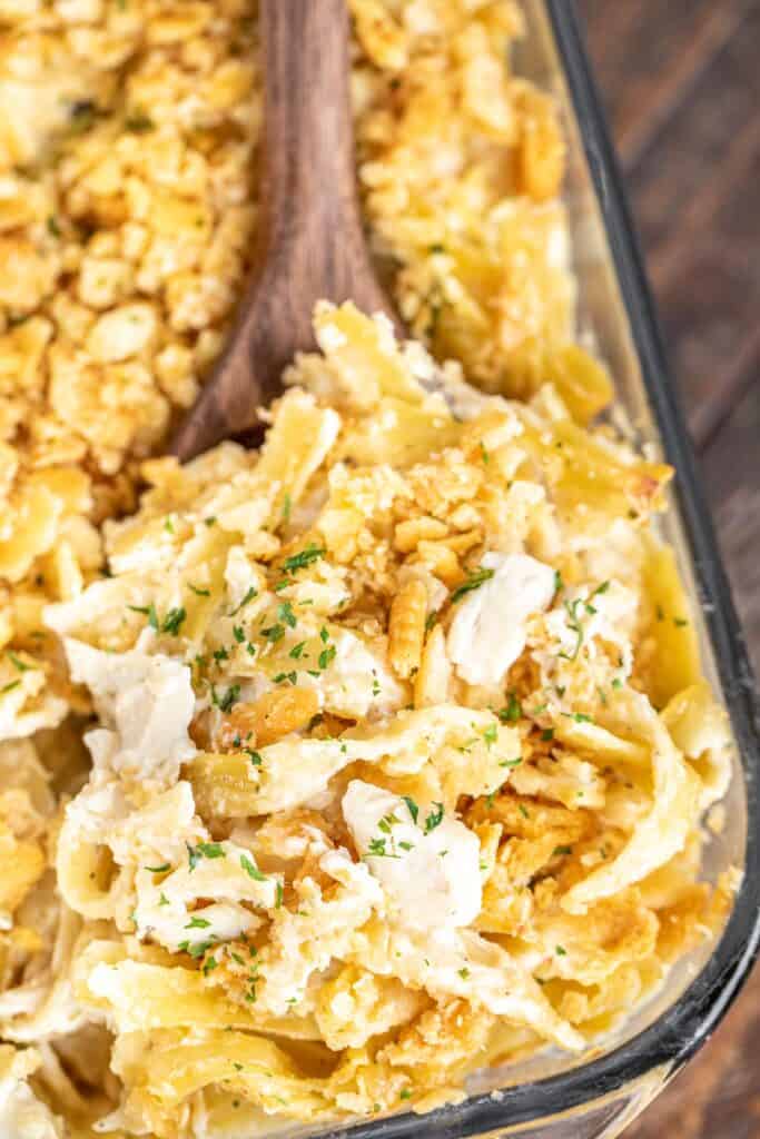 scooping chicken noodle casserole from baking dish