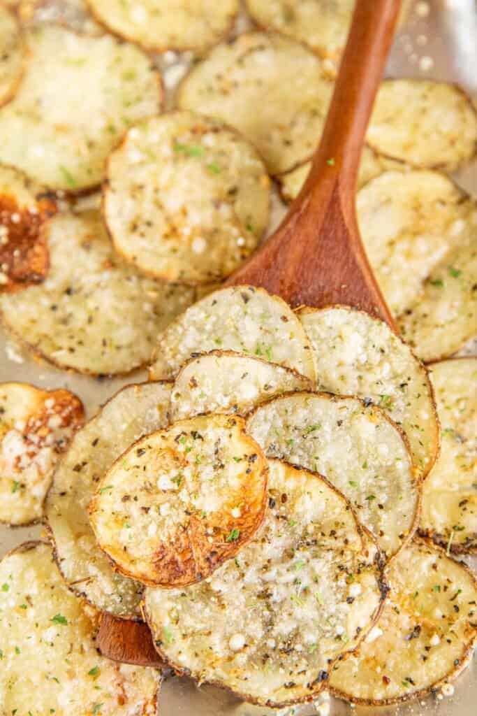 scooping baked potato slices from baking sheet