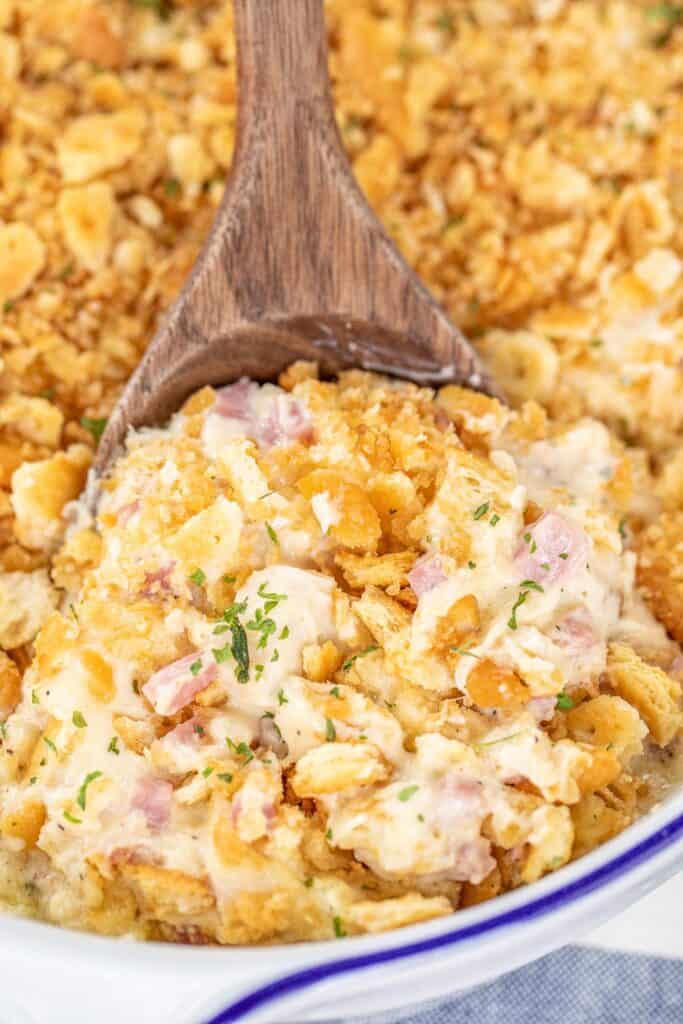 scooping chicken and ham casserole from baking dish