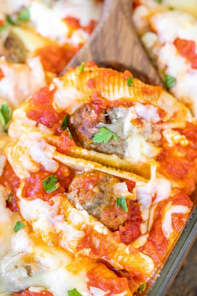 scooping stuffed shells from baking dish