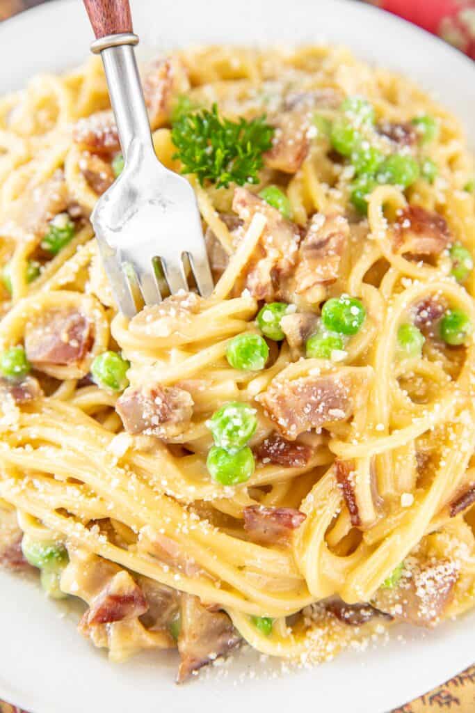 fork going into a plate of pasta with peas and bacon