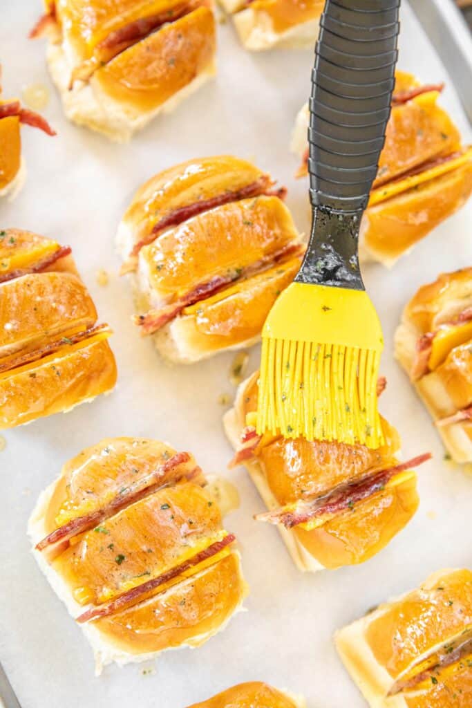 brushing cheese and bacon stuffed hawaiian rolls with butter