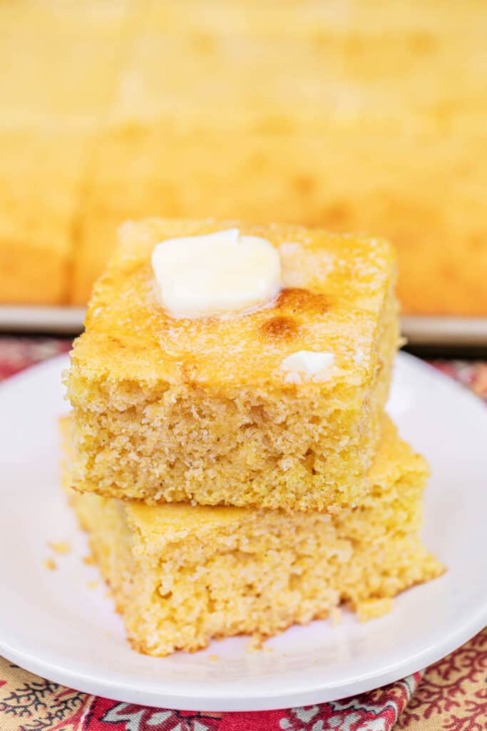 stack of cornbread on a plate topped with butter