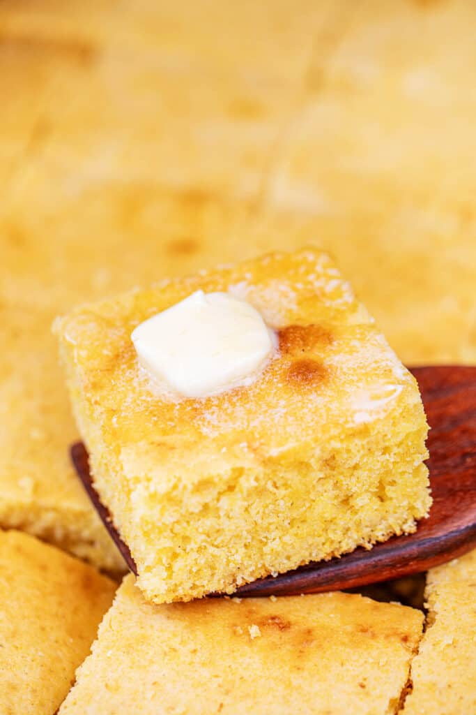 slice of cornbread on a spatula topped with butter