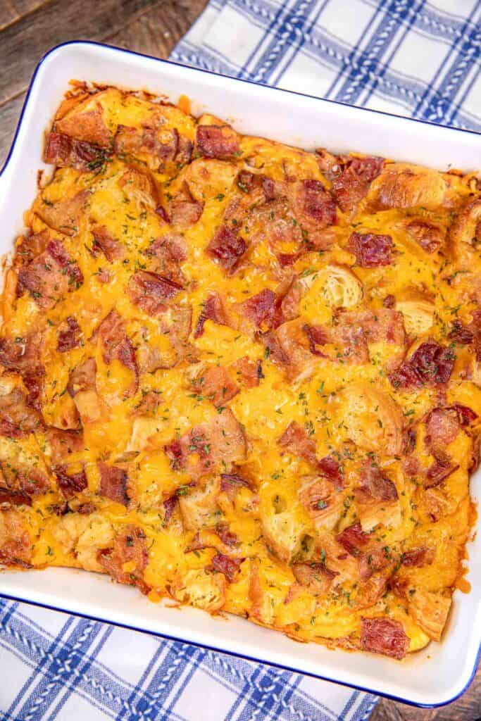 bacon croissant breakfast casserole in a baking dish on a blue and white towel