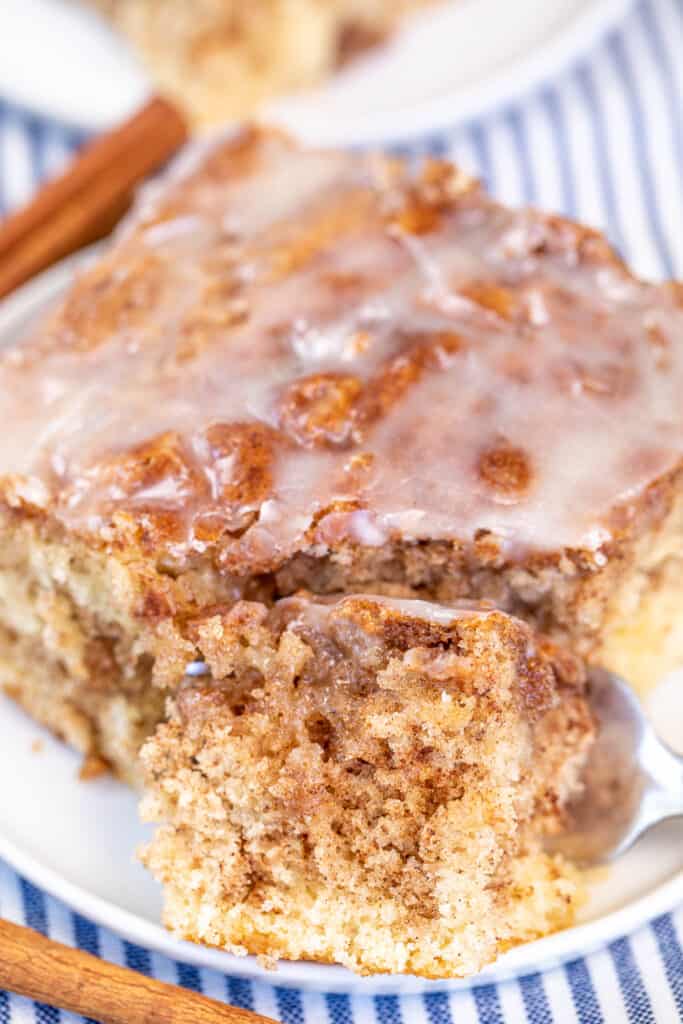 cutting into a slice of cinnamon roll cake on a plate
