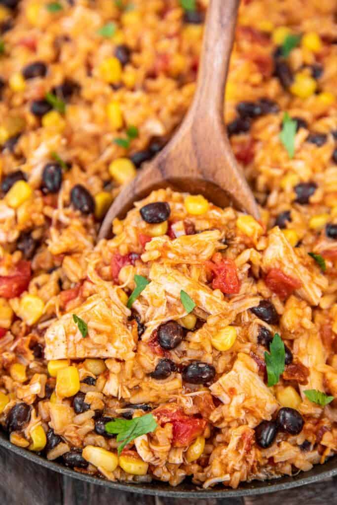 scooping chicken enchilada rice from skillet