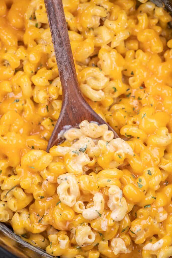 scooping macaroni and cheese from slow cooker
