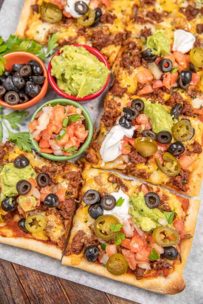 taco pizza topped with jalapeños and guacamole
