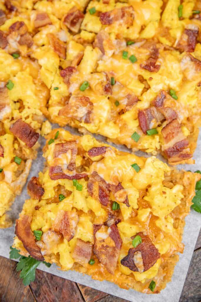 Slice of hash brown crust pizza with bacon, cheese, and eggs