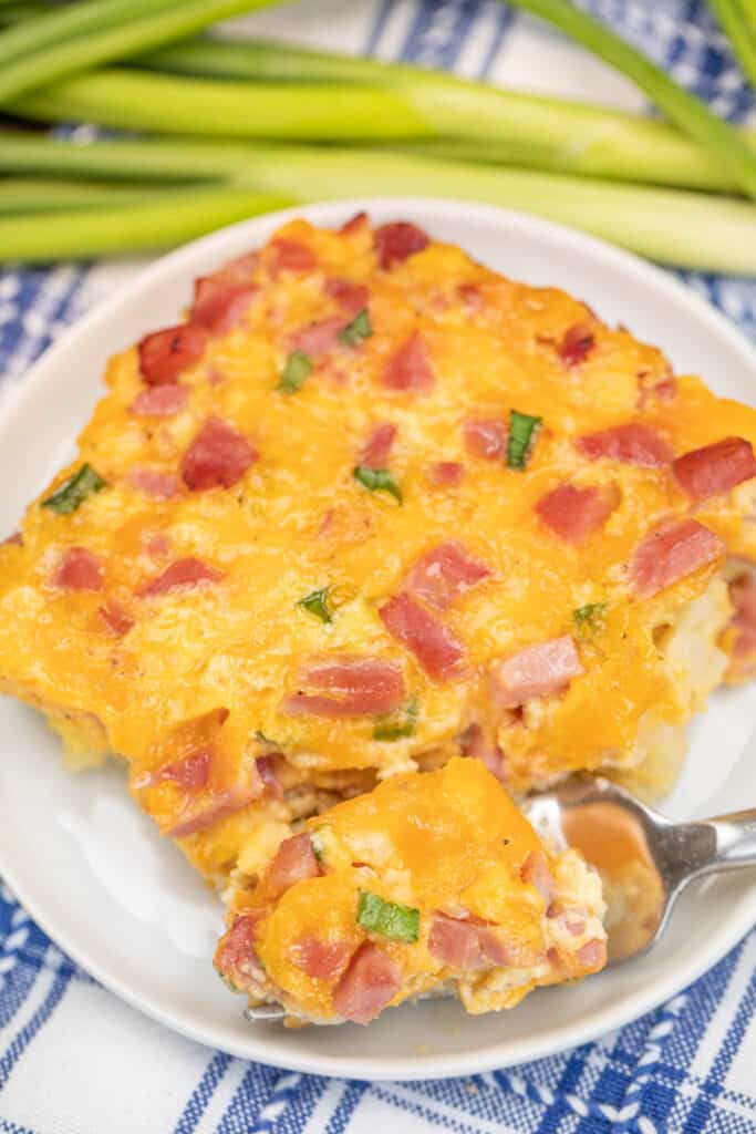 cutting into a slice of breakfast casserole with a fork