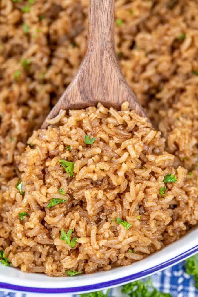 scooping brown rice from baking dish