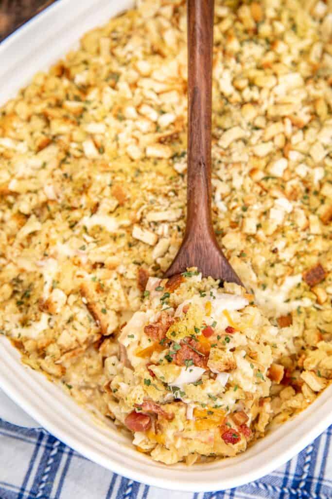 scooping chicken and stuffing casserole from baking dish