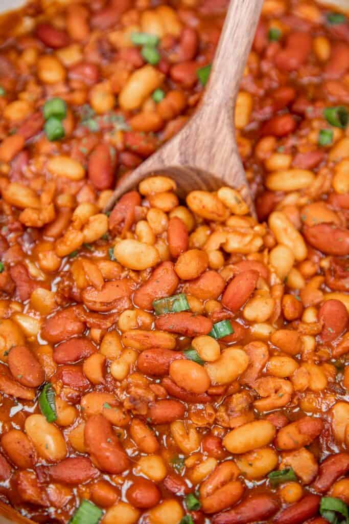 scooping dr pepper baked beans from dutch oven