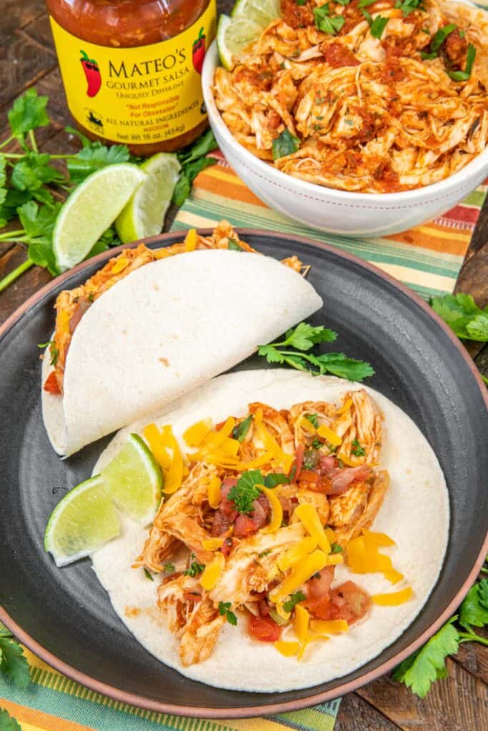 shredded chicken taco on a plate with limes
