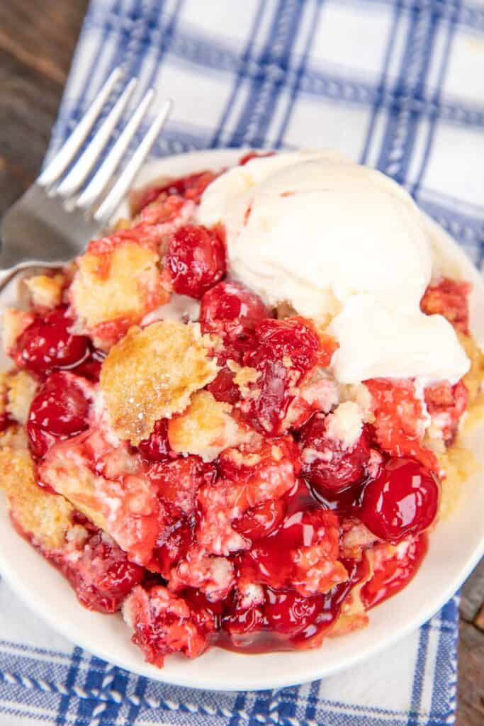 plate of cherry cheesecake dump cake topped with ice cream