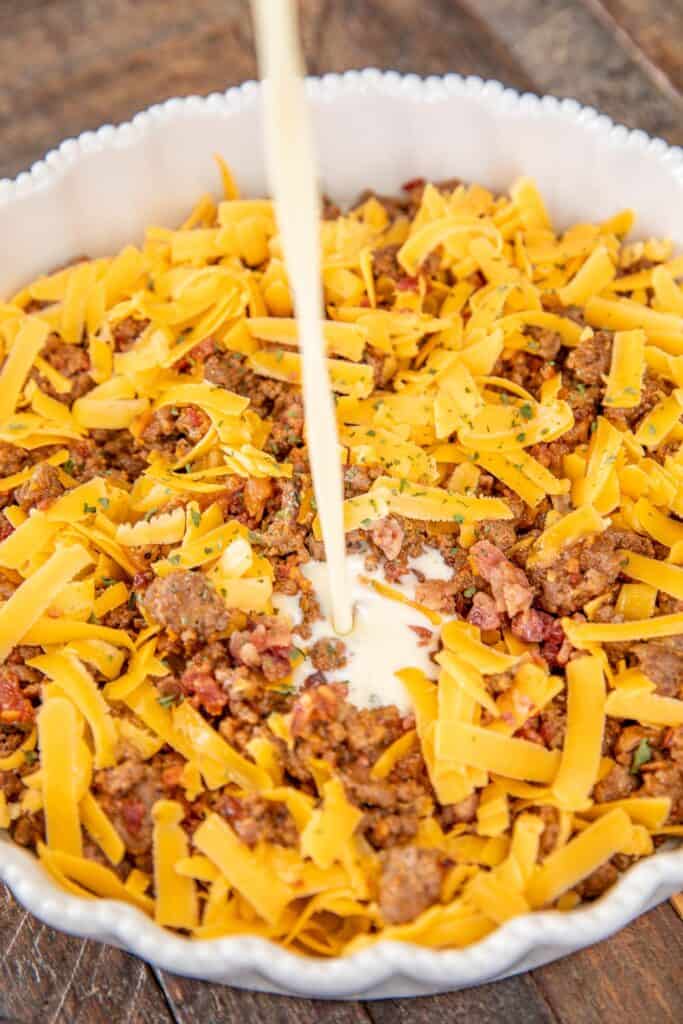 pouring bisquick custard over bacon, cheese and ground beef in a baking dish