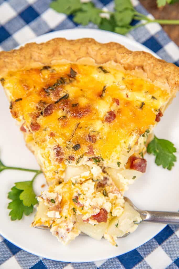 cutting into a slice of quiche on a plate