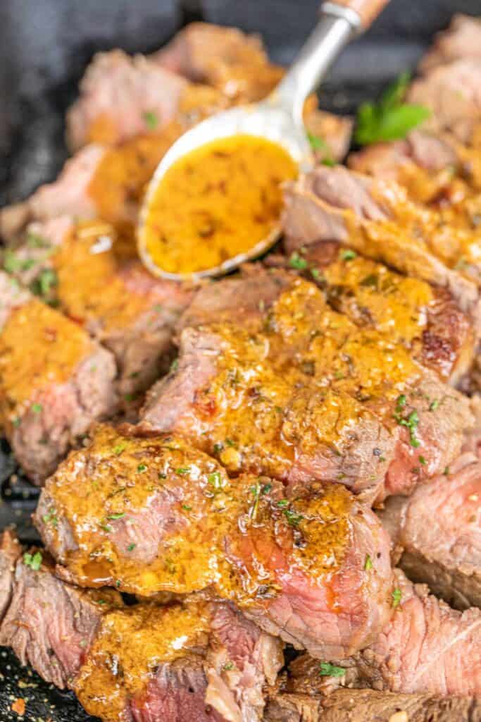 pouring butter sauce over cooked steak slices