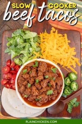bowl of shredded mexican beef on a platter with cheese, lettuce, tortillas, tomatoes, and jalapenos with text overlay