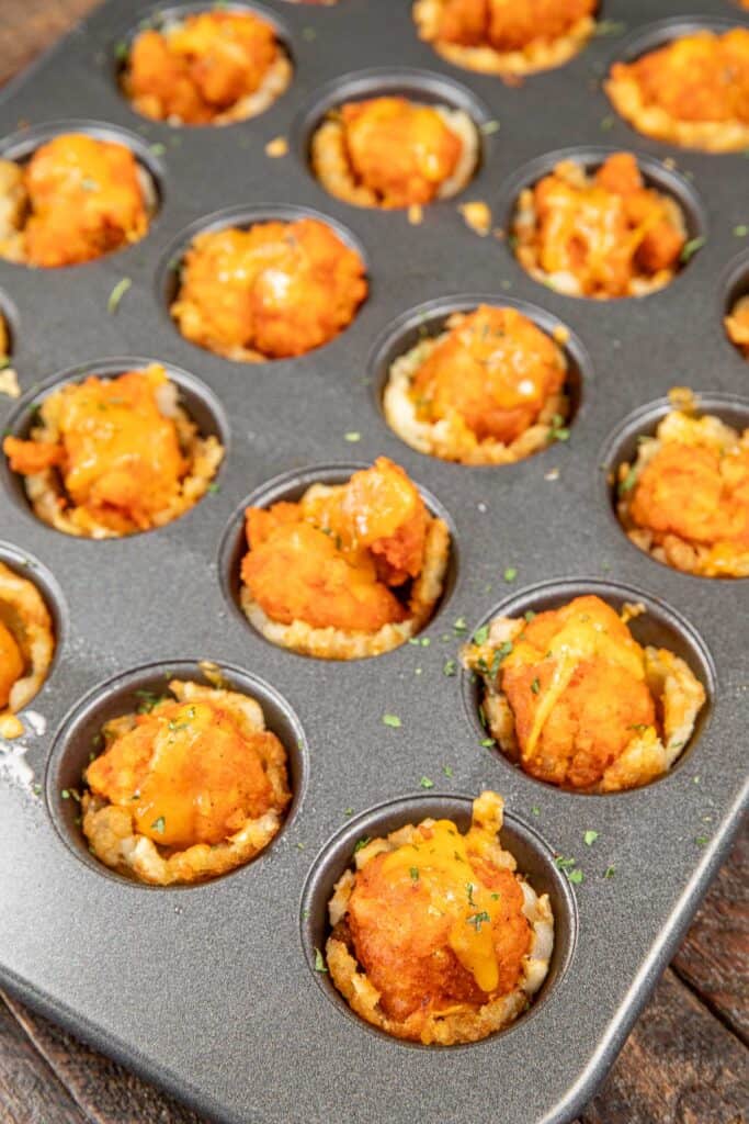 tater tot cups stuffed with buffalo chicken nuggets in a muffin pan