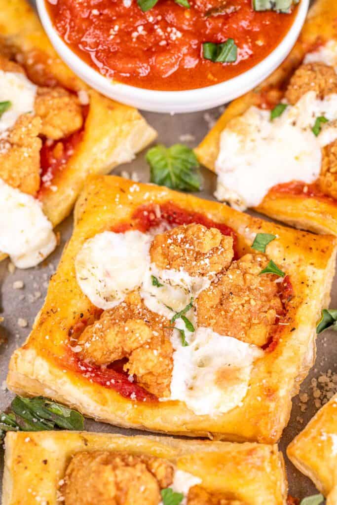 chicken parmesan puff pastry bites on a baking tray with pizza sauce