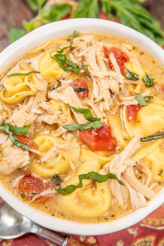 bowl of chicken tortellini soup topped with basil
