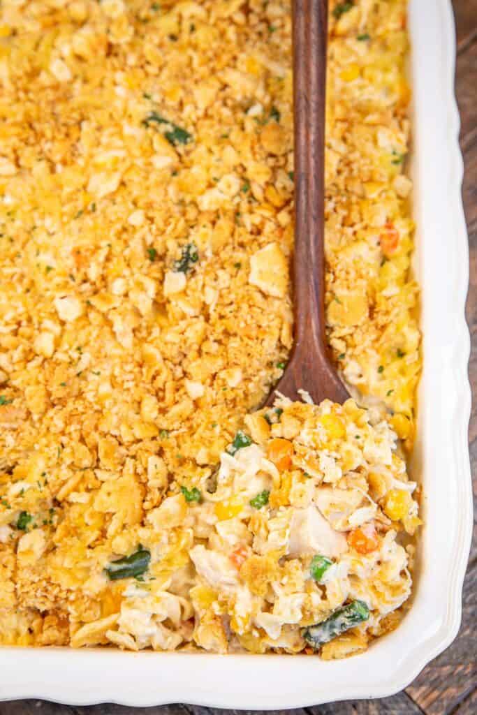 scooping chicken noodle casserole from baking dish