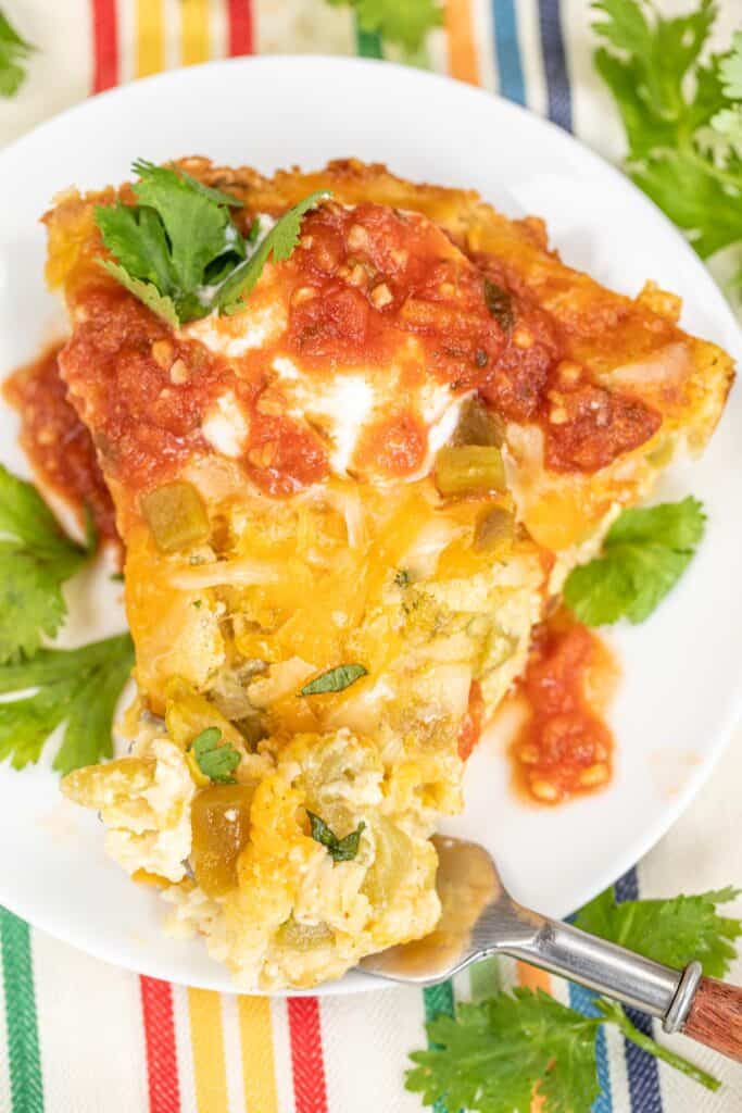 cutting into a slice of chili relleno casserole on a plate