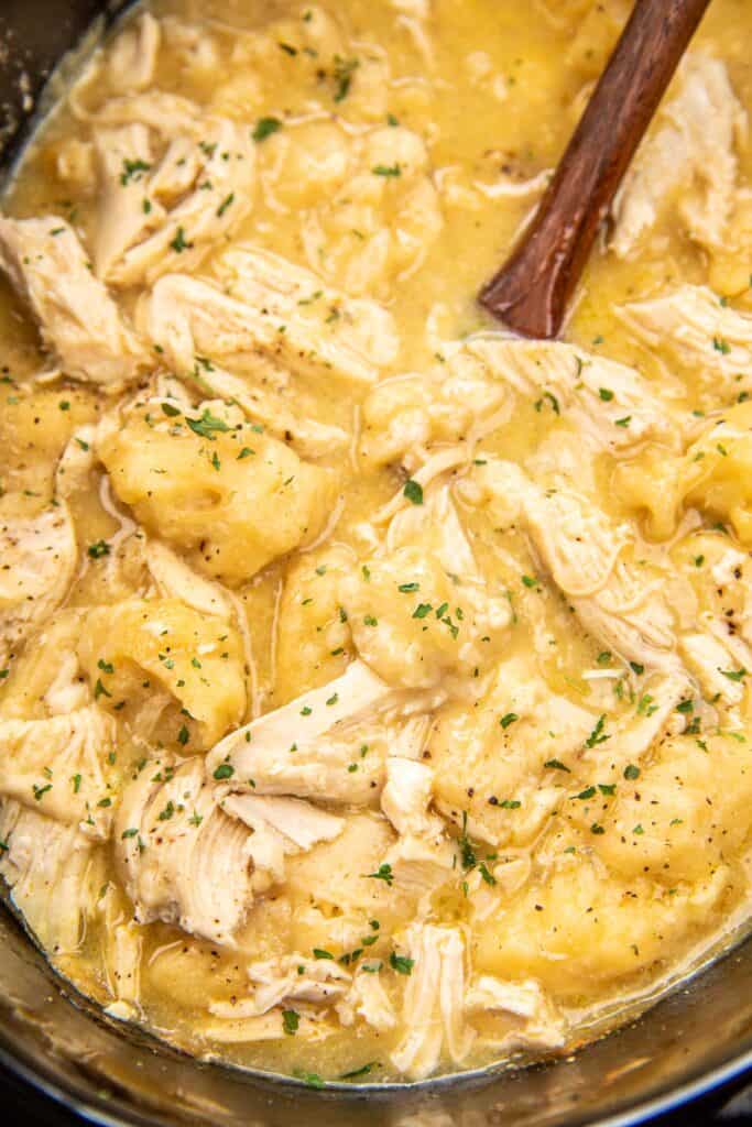 scooping chicken and dumplings from a slow cooker