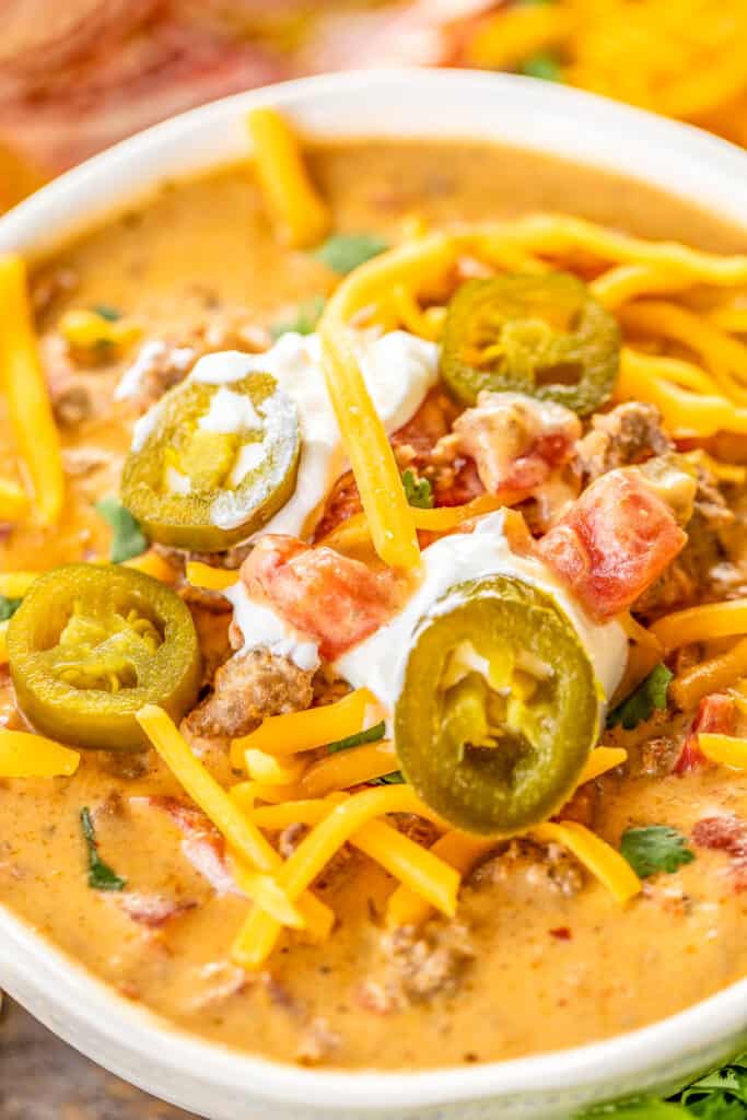 bowl of keto taco soup topped with cheese, sour cream, and jalapenos