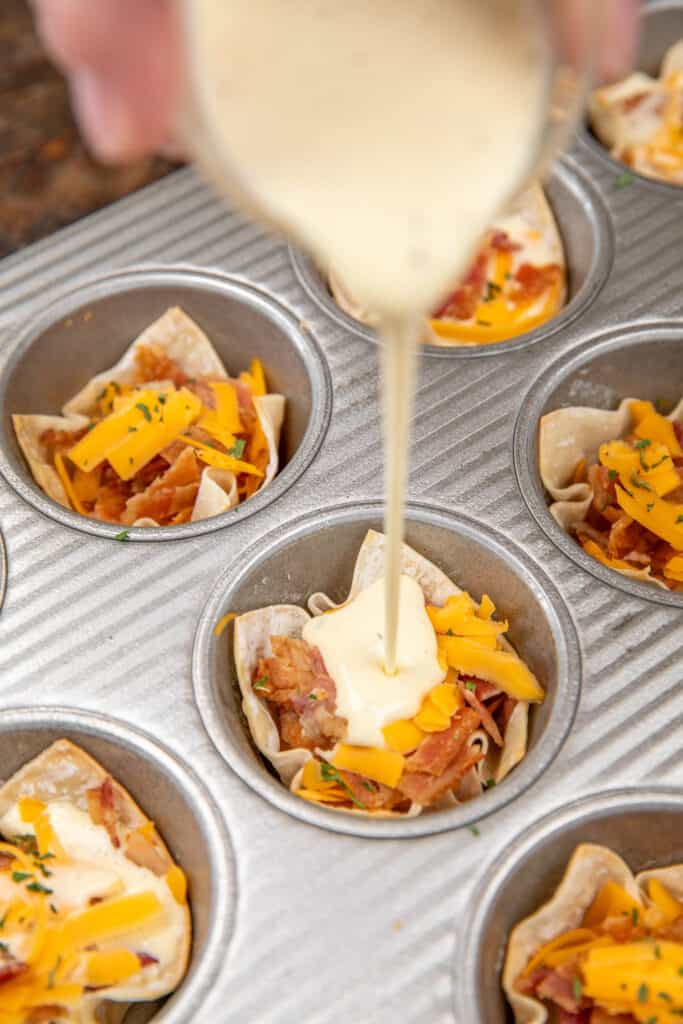 pouring egg custard over bacon and cheese in wontons in a muffin pan