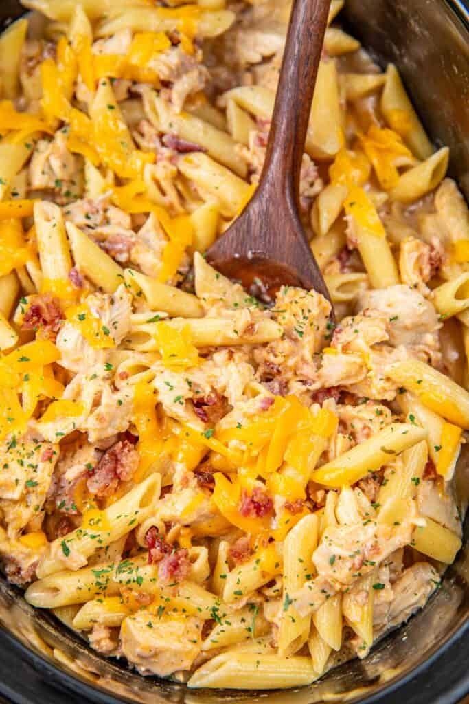 scooping cheddar bacon ranch chicken pasta from crockpot