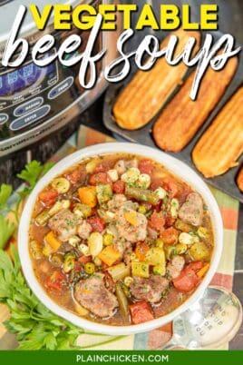 bowl of vegetable beef soup in front of cornbread sticks and a crockpot on a table with text overlay