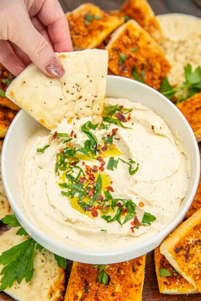 scooping whipped feta dip from a bowl onto pita bread slices