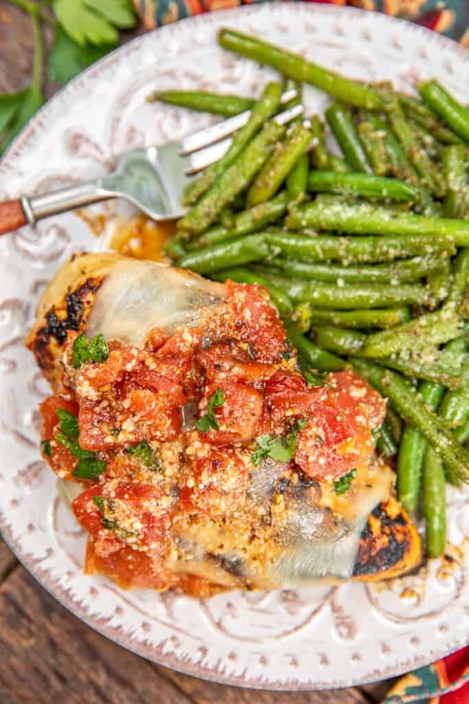 plate of bruschetta chicken with green beans and a roll