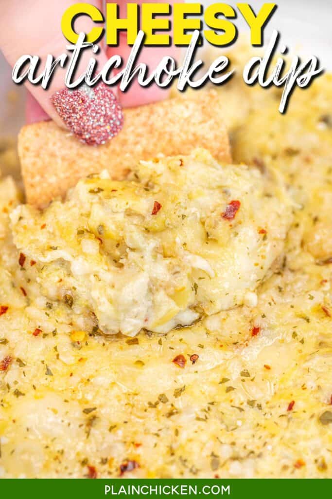 scooping cheesy artichoke dip from a baking dish with a wheat thin cracker with text overlay