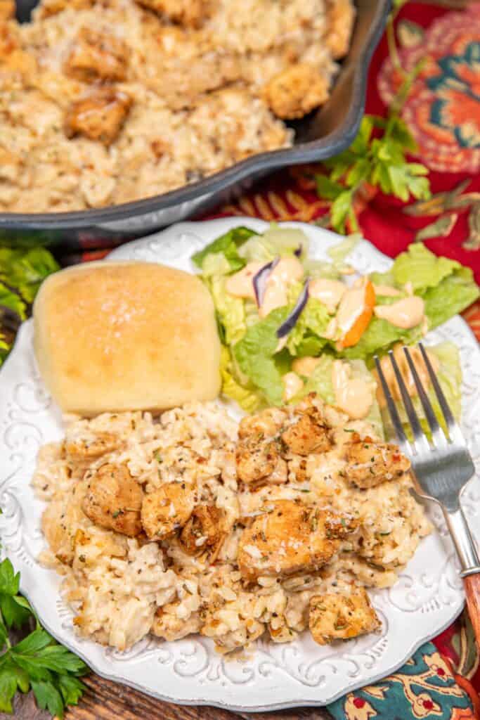 plate of chicken and rice with salad and a roll