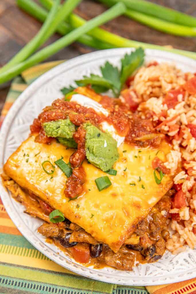 plate of taco lasagna topped with guacamole, salsa, and sour cream