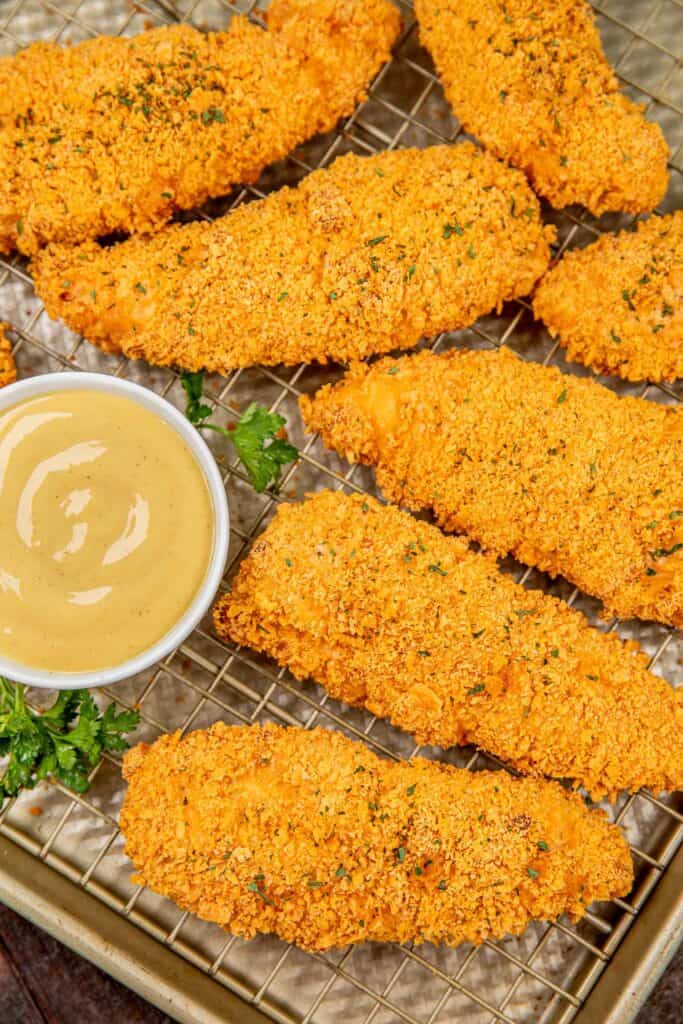 baked chicken tenders on a baking sheet with honey mustard